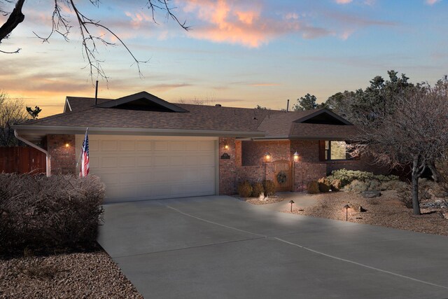 single story home featuring a gate, fence, concrete driveway, an attached garage, and a shingled roof