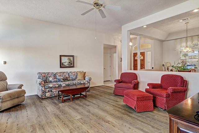 living room featuring hardwood / wood-style flooring, ceiling fan, and a textured ceiling