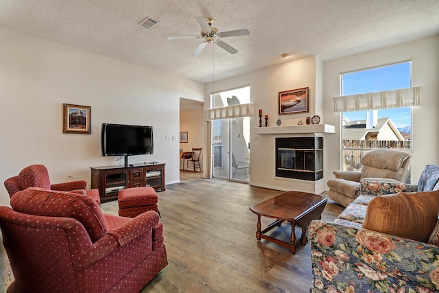 living room featuring ceiling fan, hardwood / wood-style floors, and a textured ceiling