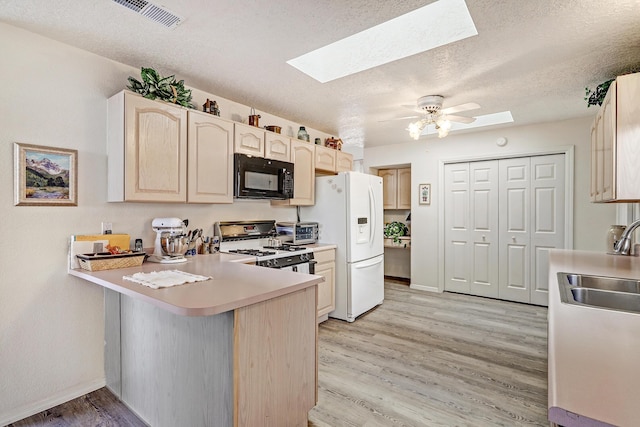 kitchen with sink, a skylight, light hardwood / wood-style flooring, kitchen peninsula, and white appliances