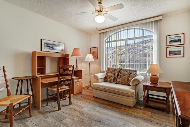 living area featuring hardwood / wood-style flooring, a textured ceiling, and ceiling fan