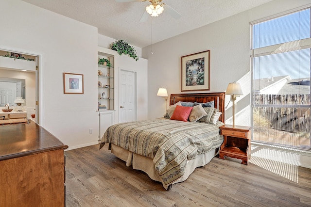 bedroom with ceiling fan, wood-type flooring, and a textured ceiling