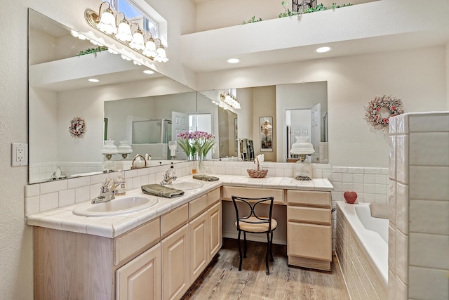 bathroom featuring vanity, tiled tub, backsplash, and wood-type flooring