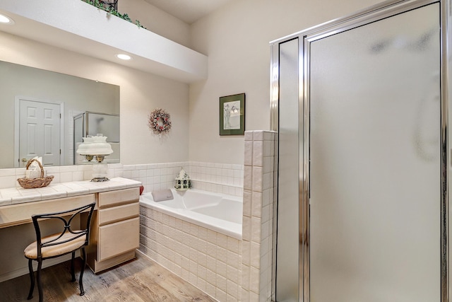 bathroom featuring hardwood / wood-style flooring, plus walk in shower, and vanity