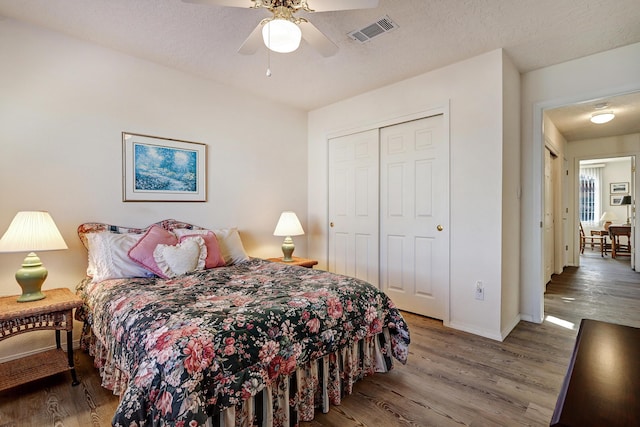 bedroom with a closet, dark hardwood / wood-style floors, a textured ceiling, and ceiling fan