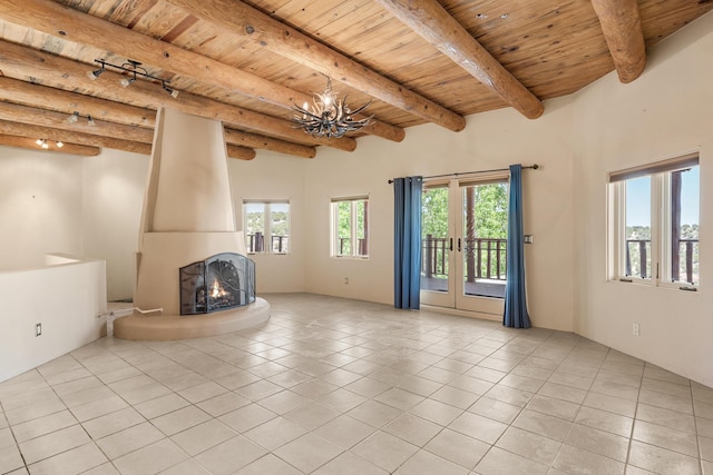22 Del Charro Rd, Lamy, NM 87540 - unfurnished living room featuring light tile patterned flooring, beamed ceiling, a large fireplace, a notable chandelier, and wooden ceiling