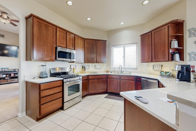 kitchen with light tile patterned flooring, stainless steel appliances, kitchen peninsula, and sink