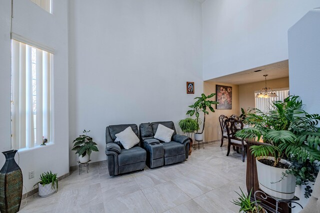 living room featuring a high ceiling, plenty of natural light, and an inviting chandelier