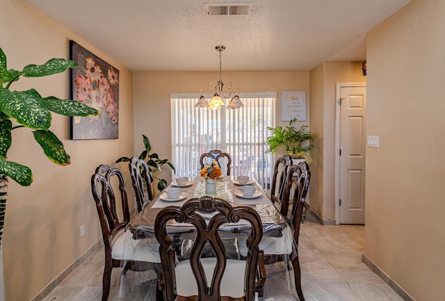 dining space featuring a notable chandelier and a textured ceiling