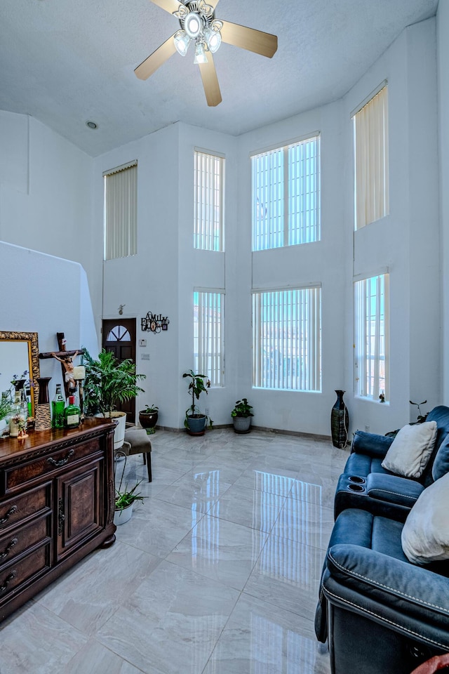 living room featuring ceiling fan, a towering ceiling, and a textured ceiling