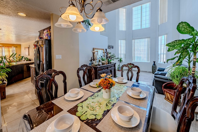 dining area featuring an inviting chandelier, light tile patterned flooring, and a textured ceiling