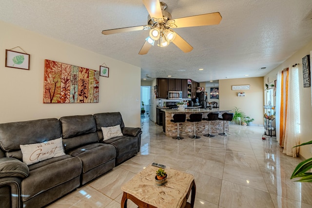 living room featuring ceiling fan, sink, and a textured ceiling