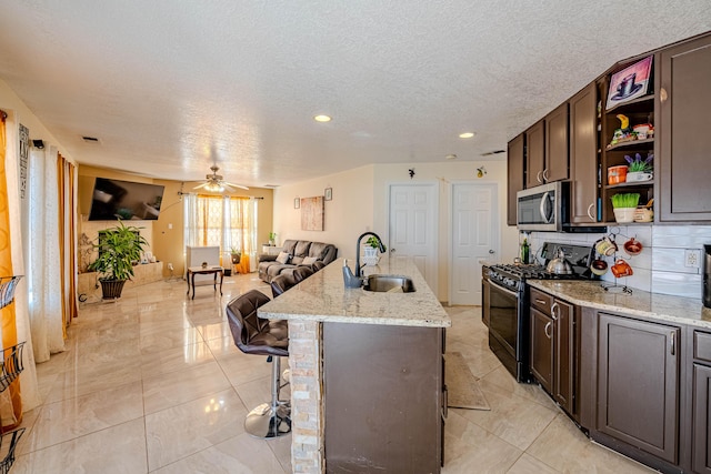 kitchen featuring sink, a breakfast bar area, range with gas stovetop, and an island with sink