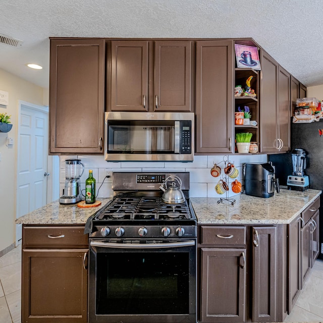 kitchen with tasteful backsplash, appliances with stainless steel finishes, light stone countertops, and dark brown cabinets