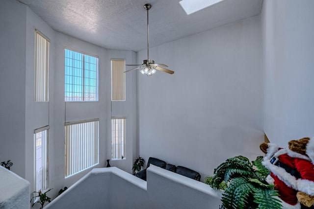 interior details with ceiling fan, a skylight, and a textured ceiling