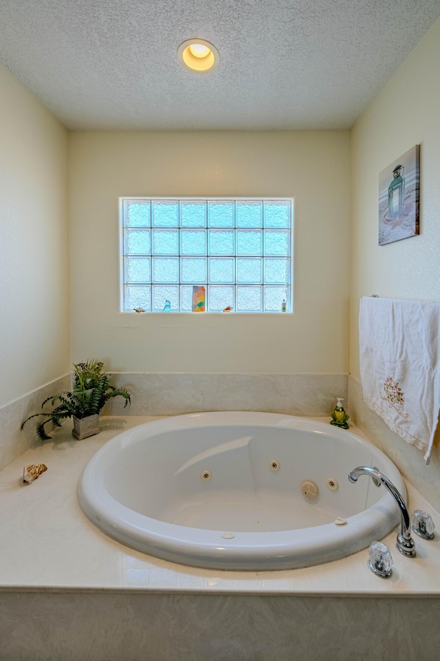 bathroom featuring tiled bath and a textured ceiling