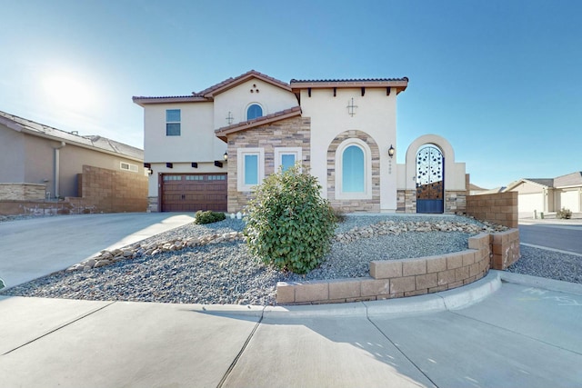 mediterranean / spanish-style home featuring stone siding, fence, driveway, and stucco siding