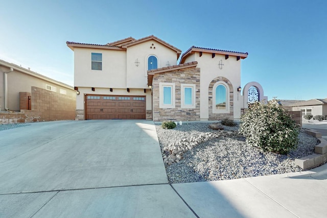 mediterranean / spanish-style house featuring stucco siding, concrete driveway, an attached garage, stone siding, and a tiled roof