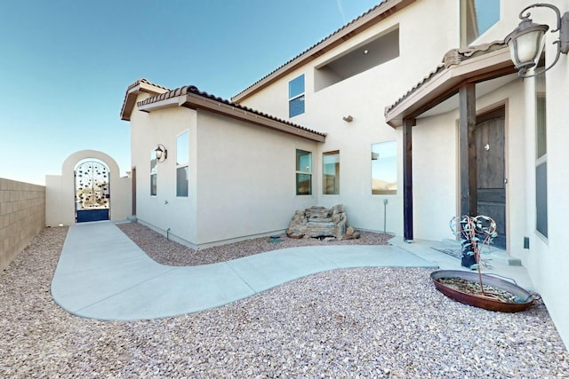 rear view of property with a patio, fence, a tiled roof, and stucco siding