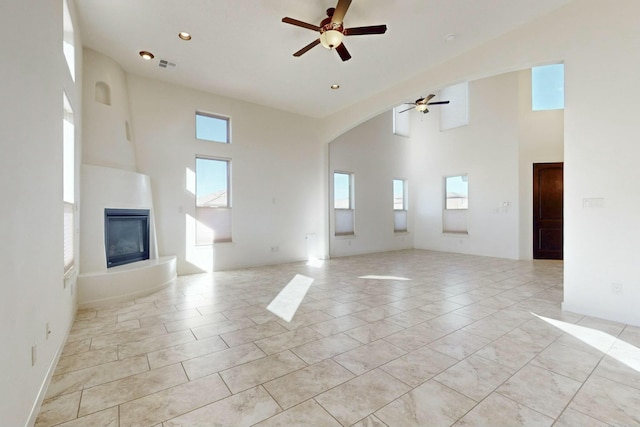 unfurnished living room with a large fireplace, visible vents, ceiling fan, a high ceiling, and recessed lighting