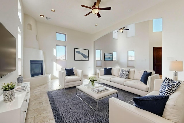 living area featuring recessed lighting, a large fireplace, ceiling fan, and a high ceiling