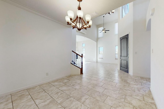 empty room featuring light tile patterned floors, arched walkways, a towering ceiling, stairway, and ornamental molding