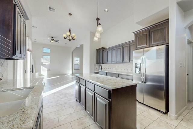 kitchen featuring dark brown cabinetry, stainless steel fridge, visible vents, arched walkways, and backsplash