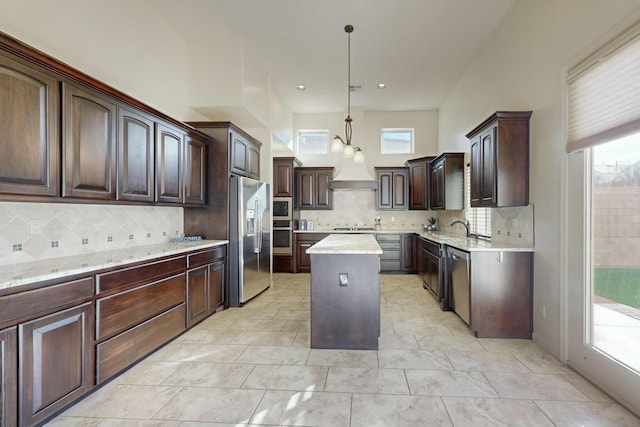 kitchen featuring dark brown cabinetry, decorative backsplash, a center island, hanging light fixtures, and stainless steel appliances