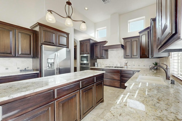 kitchen featuring appliances with stainless steel finishes, premium range hood, a sink, and light stone countertops