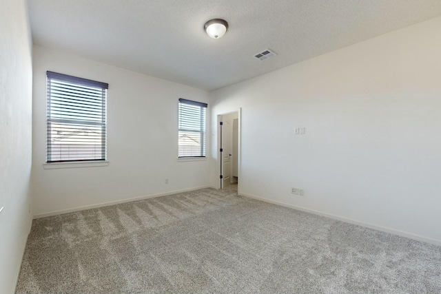 unfurnished room with baseboards, visible vents, and light colored carpet