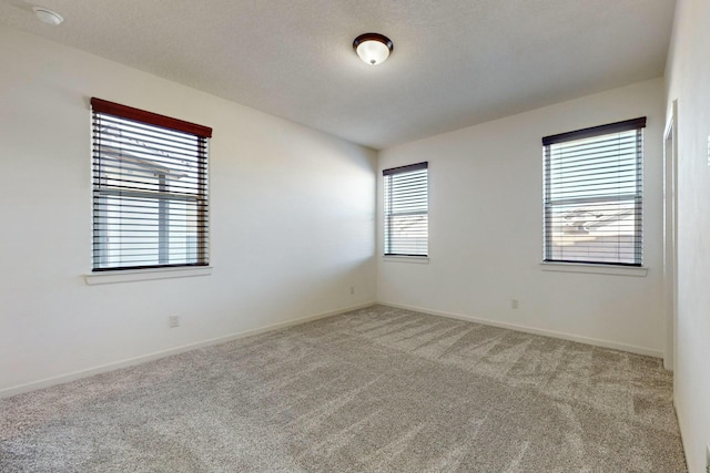 carpeted spare room with baseboards and a textured ceiling