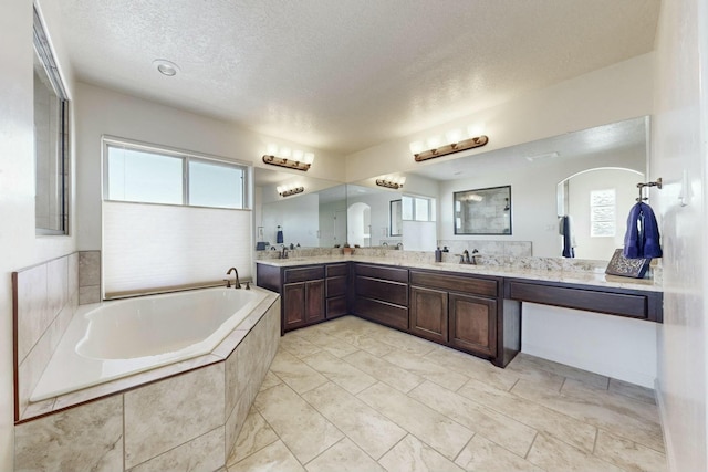 bathroom featuring a textured ceiling, vanity, and a bath