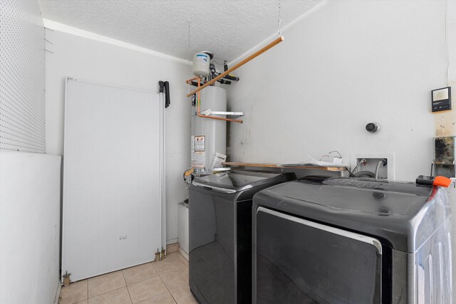 clothes washing area featuring light tile patterned floors, a textured ceiling, water heater, and washing machine and clothes dryer