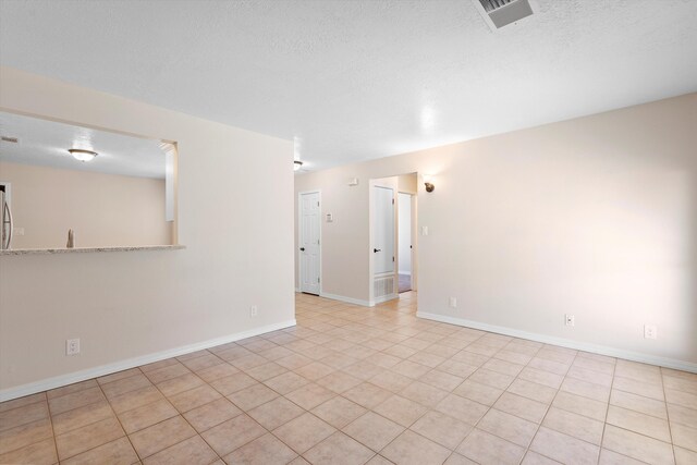 tiled spare room with a textured ceiling