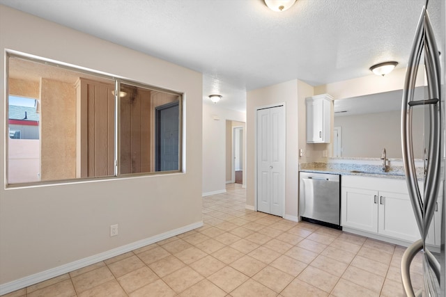 kitchen featuring sink, appliances with stainless steel finishes, a textured ceiling, light tile patterned flooring, and white cabinets