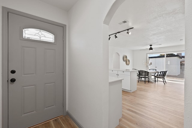 entryway featuring ceiling fan, track lighting, a textured ceiling, and light hardwood / wood-style flooring