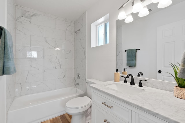 full bathroom with tiled shower / bath combo, vanity, hardwood / wood-style flooring, and toilet