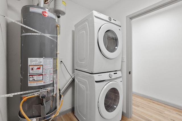 washroom with stacked washer and dryer, water heater, and light wood-type flooring