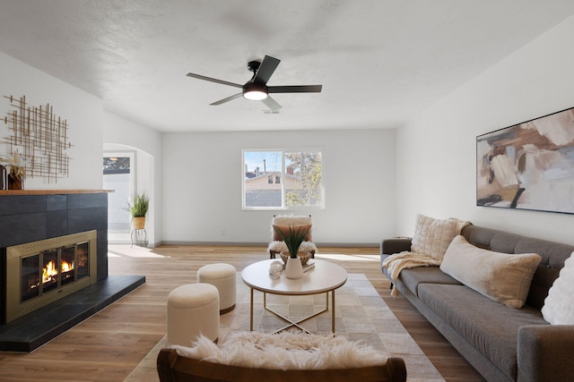 living room featuring hardwood / wood-style flooring, ceiling fan, and a fireplace