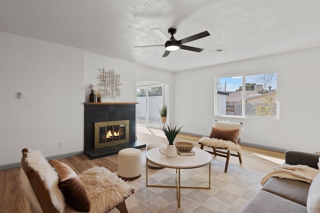 living room featuring a textured ceiling, light hardwood / wood-style floors, and ceiling fan