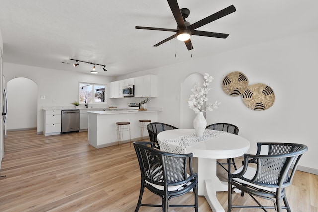 dining space with ceiling fan, sink, and light wood-type flooring