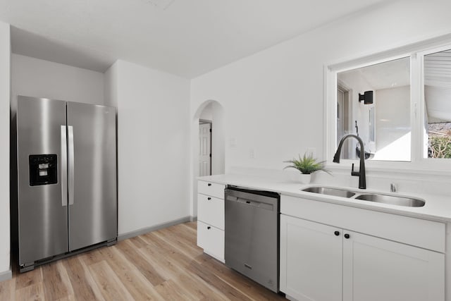 kitchen with sink, light hardwood / wood-style floors, white cabinets, and appliances with stainless steel finishes