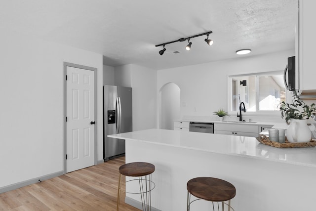 kitchen featuring sink, a breakfast bar area, kitchen peninsula, stainless steel appliances, and light wood-type flooring