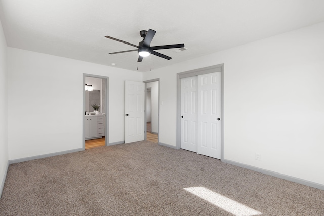 unfurnished bedroom featuring ceiling fan, light colored carpet, connected bathroom, and a closet