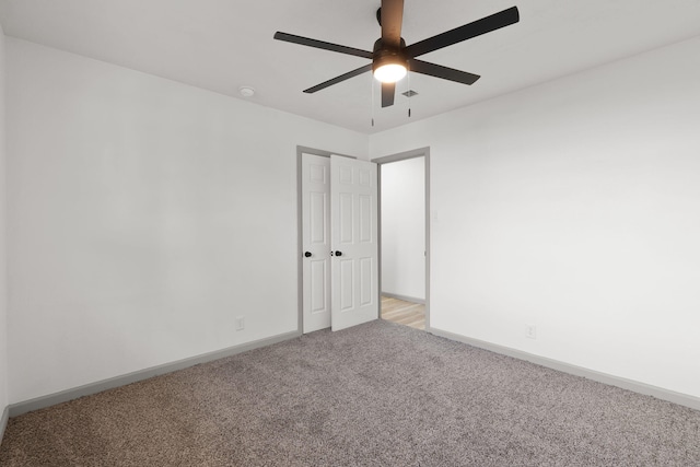 carpeted spare room featuring ceiling fan