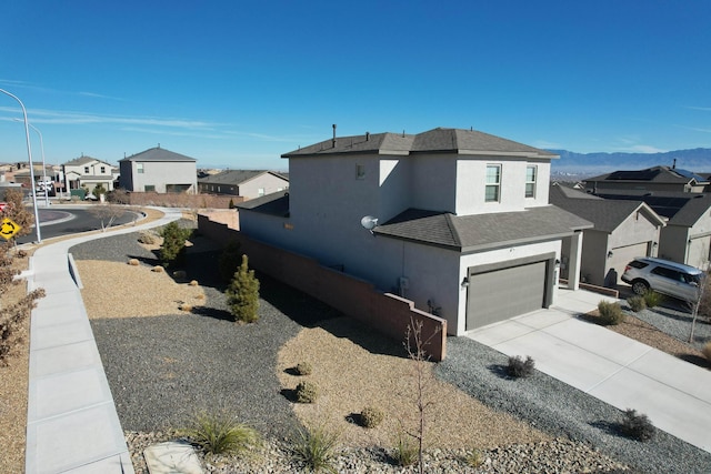 view of property exterior featuring stucco siding, a shingled roof, a garage, a residential view, and driveway