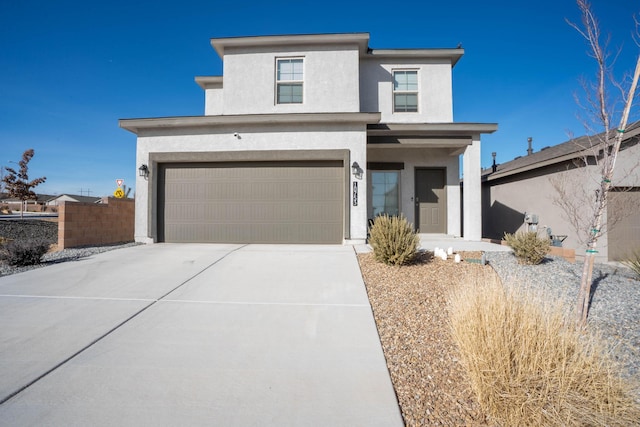 view of front of home with a garage, driveway, fence, and stucco siding