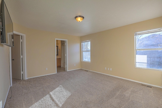 unfurnished bedroom with ensuite bath and light carpet