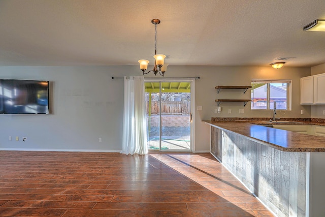 kitchen featuring sink, dark wood-type flooring, white cabinetry, hanging light fixtures, and kitchen peninsula