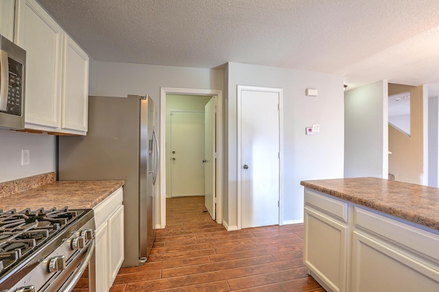 kitchen with white cabinetry, stainless steel appliances, dark wood-type flooring, and a textured ceiling